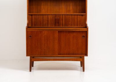 Teak bookcase/desk by Johannes Sorth for Borholms Møbelfabrik (Denmark, 1960s). A well-known and super multi functional design with a high quality standard. Featuring two sliding doors with lots of storage space inside, a convenient pull-out leaf, super detailed tambour doors with some storage space and drawers inside and two adjustable shelves. In very good condition with one repair spot on the right corner. Tambour doors open very smoothly. Marked by maker.