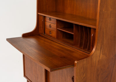 Teak bookcase/desk by Johannes Sorth for Borholms Møbelfabrik (Denmark, 1960s). A well-known and super multi functional design with a high quality standard. Featuring two sliding doors with lots of storage space inside, a convenient pull-out leaf, super detailed tambour doors with some storage space and drawers inside and two adjustable shelves. In very good condition with one repair spot on the right corner. Tambour doors open very smoothly. Marked by maker.