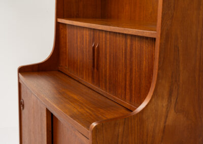 Teak bookcase/desk by Johannes Sorth for Borholms Møbelfabrik (Denmark, 1960s). A well-known and super multi functional design with a high quality standard. Featuring two sliding doors with lots of storage space inside, a convenient pull-out leaf, super detailed tambour doors with some storage space and drawers inside and two adjustable shelves. In very good condition with one repair spot on the right corner. Tambour doors open very smoothly. Marked by maker.