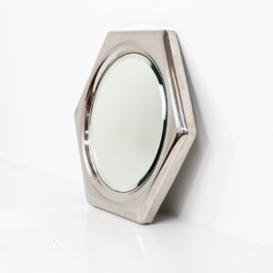 Space Age hexagon wall mirror (Italy, 1970s). A stunning piece made out of polished metal with a round inlay mirror and a beveled edge. It looks like one solid shiny piece and is a real eye catcher in the room. The mirror has several mounting points so that it can be hung in two different ways. In perfect condition.