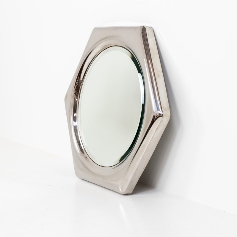 Space Age hexagon wall mirror (Italy, 1970s). A stunning piece made out of polished metal with a round inlay mirror and a beveled edge. It looks like one solid shiny piece and is a real eye catcher in the room. The mirror has several mounting points so that it can be hung in two different ways. In perfect condition.