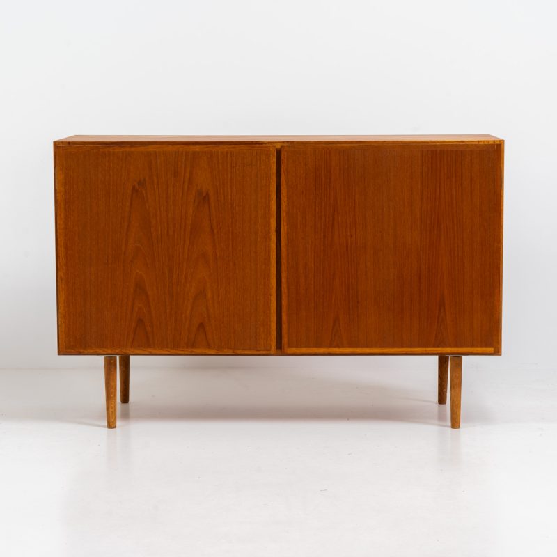 Midcentury Danish cabinet by Omann Jun (Denmark, 1960s). A sleek and convenient design with handle free doors and adjustable shelves on the inside. It’s made out of teak and features a beautiful warm woodgrain. In very good condition. Marked by maker on the back.