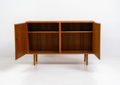 Midcentury Danish cabinet by Omann Jun (Denmark, 1960s). A sleek and convenient design with handle free doors and adjustable shelves on the inside. It’s made out of teak and features a beautiful warm woodgrain. In very good condition. Marked by maker on the back.