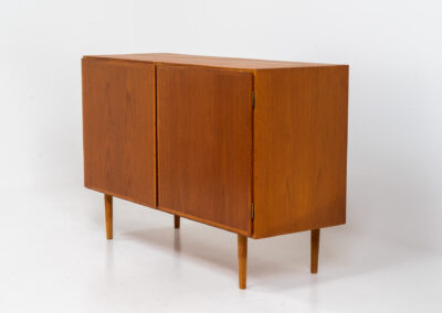 Midcentury Danish cabinet by Omann Jun (Denmark, 1960s). A sleek and convenient design with handle free doors and adjustable shelves on the inside. It’s made out of teak and features a beautiful warm woodgrain. In very good condition. Marked by maker on the back.