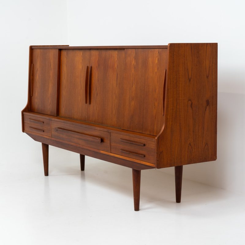 Beautiful sideboard by Tylvad Hansen in teak (Denmark, 1960s). It contains four sliding doors, four small drawers and one big drawer. On the inside there are three adjustable shelves and a bar unit with four small drawers. Featuring a very nice warm woodgrain and beautiful handels. In very good condition.