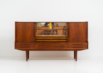 Beautiful sideboard by Tylvad Hansen in teak (Denmark, 1960s). It contains four sliding doors, four small drawers and one big drawer. On the inside there are three adjustable shelves and a bar unit with four small drawers. Featuring a very nice warm woodgrain and beautiful handels. In very good condition.
