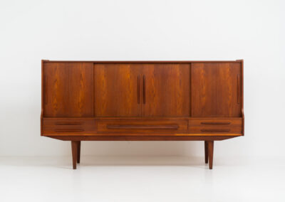 Beautiful sideboard by Tylvad Hansen in teak (Denmark, 1960s). It contains four sliding doors, four small drawers and one big drawer. On the inside there are three adjustable shelves and a bar unit with four small drawers. Featuring a very nice warm woodgrain and beautiful handels. In very good condition.