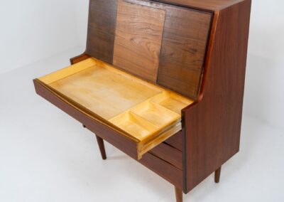 Teak secretary in the manner of Arne Vodder (Denmark, 1960s). A highly versatile piece featuring beautiful handles, a pull-out leaf and lots of storage space. A small and convenient piece that finds its way in any setting. In very good condition!