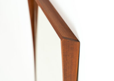 Elegant Mid-Century wall mirror (Denmark, 1960s). Featuring a beautiful organic frame in solid teak, a black trim and a faceted glass mirror. The combination of the curved frame and the black trim makes this mirror a pleasure for the eyes! In very good condition.