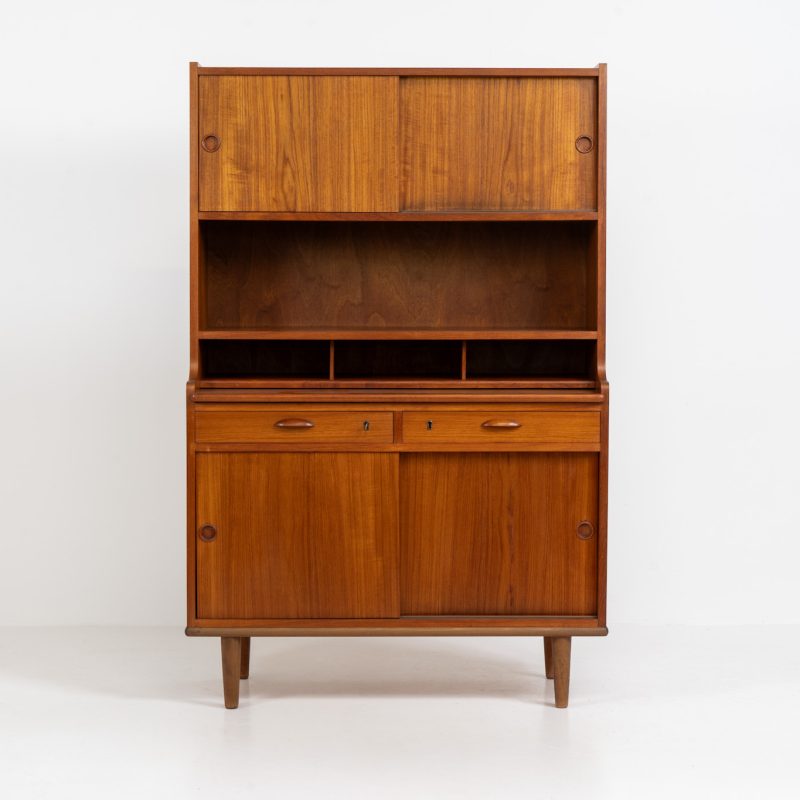 Teak secretary/bookcase by Harald Nielsen (Denmark, 1960s). A nicely designed and multifunctional piece containing four sliding doors, two drawers, a convenient pull-out leaf and some open storage space. Featuring nice handles and a warm natural wood grain. It is in splendid condition and the original key is included.