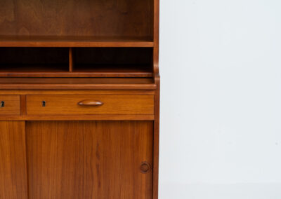 Teak secretary/bookcase by Harald Nielsen (Denmark, 1960s). A nicely designed and multifunctional piece containing four sliding doors, two drawers, a convenient pull-out leaf and some open storage space. Featuring nice handles and a warm natural wood grain. It is in splendid condition and the original key is included.