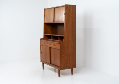 Teak secretary/bookcase by Harald Nielsen (Denmark, 1960s). A nicely designed and multifunctional piece containing four sliding doors, two drawers, a convenient pull-out leaf and some open storage space. Featuring nice handles and a warm natural wood grain. It is in splendid condition and the original key is included.