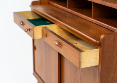Teak secretary/bookcase by Harald Nielsen (Denmark, 1960s). A nicely designed and multifunctional piece containing four sliding doors, two drawers, a convenient pull-out leaf and some open storage space. Featuring nice handles and a warm natural wood grain. It is in splendid condition and the original key is included.