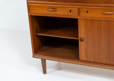 Teak secretary/bookcase by Harald Nielsen (Denmark, 1960s). A nicely designed and multifunctional piece containing four sliding doors, two drawers, a convenient pull-out leaf and some open storage space. Featuring nice handles and a warm natural wood grain. It is in splendid condition and the original key is included.