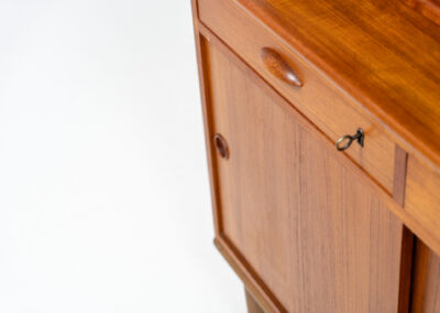 Teak secretary/bookcase by Harald Nielsen (Denmark, 1960s). A nicely designed and multifunctional piece containing four sliding doors, two drawers, a convenient pull-out leaf and some open storage space. Featuring nice handles and a warm natural wood grain. It is in splendid condition and the original key is included.