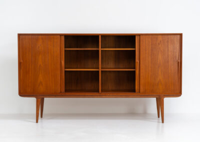 “Model 19” sideboard by Gunni Omann for Omann Jun (Denmark, 1960s). A high end teak piece containing four sliding doors, lots of storage space and eight convenient drawers on the inside. The combination of the typical Gunni Omann handles, the organic shapes and the warm golden woodgrain makes this a stunning Piece! The back is veneered aswell so it can be placed in the center of the room as a room divider for example. In very good condition, one of the handles has worn off a bit as shown on the pictures.