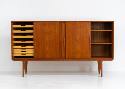 “Model 19” sideboard by Gunni Omann for Omann Jun (Denmark, 1960s). A high end teak piece containing four sliding doors, lots of storage space and eight convenient drawers on the inside. The combination of the typical Gunni Omann handles, the organic shapes and the warm golden woodgrain makes this a stunning Piece! The back is veneered aswell so it can be placed in the center of the room as a room divider for example. In very good condition, one of the handles has worn off a bit as shown on the pictures.