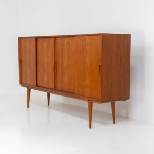 “Model 19” sideboard by Gunni Omann for Omann Jun (Denmark, 1960s). A high end teak piece containing four sliding doors, lots of storage space and eight convenient drawers on the inside. The combination of the typical Gunni Omann handles, the organic shapes and the warm golden woodgrain makes this a stunning Piece! The back is veneered aswell so it can be placed in the center of the room as a room divider for example. In very good condition, one of the handles has worn off a bit as shown on the pictures.