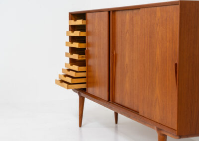 “Model 19” sideboard by Gunni Omann for Omann Jun (Denmark, 1960s). A high end teak piece containing four sliding doors, lots of storage space and eight convenient drawers on the inside. The combination of the typical Gunni Omann handles, the organic shapes and the warm golden woodgrain makes this a stunning Piece! The back is veneered aswell so it can be placed in the center of the room as a room divider for example. In very good condition, one of the handles has worn off a bit as shown on the pictures.