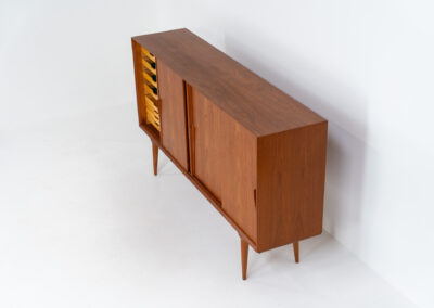 “Model 19” sideboard by Gunni Omann for Omann Jun (Denmark, 1960s). A high end teak piece containing four sliding doors, lots of storage space and eight convenient drawers on the inside. The combination of the typical Gunni Omann handles, the organic shapes and the warm golden woodgrain makes this a stunning Piece! The back is veneered aswell so it can be placed in the center of the room as a room divider for example. In very good condition, one of the handles has worn off a bit as shown on the pictures.