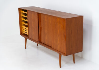 “Model 19” sideboard by Gunni Omann for Omann Jun (Denmark, 1960s). A high end teak piece containing four sliding doors, lots of storage space and eight convenient drawers on the inside. The combination of the typical Gunni Omann handles, the organic shapes and the warm golden woodgrain makes this a stunning Piece! The back is veneered aswell so it can be placed in the center of the room as a room divider for example. In very good condition, one of the handles has worn off a bit as shown on the pictures.