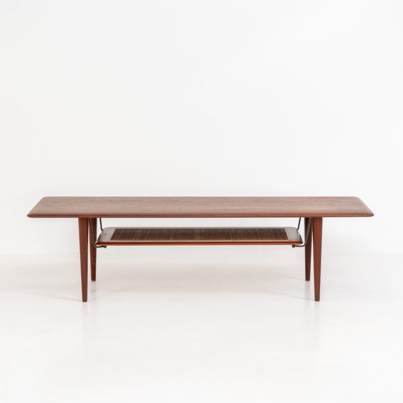 Highly collectible FD-516 coffee table by Peter Hvidt & Orla Mølgaard for France & Søn (Denmark, 1960s). This rare and important FD-516 model features a solid teak table top and solid legs. It has an additional magazine area made of rattan mesh, which is worn by brass fittings. An example of a highly detailed and high quality Scandinavian design classic in very good condition. Marked by maker.