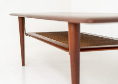 Highly collectible FD-516 coffee table by Peter Hvidt & Orla Mølgaard for France & Søn (Denmark, 1960s). This rare and important FD-516 model features a solid teak table top and solid legs. It has an additional magazine area made of rattan mesh, which is worn by brass fittings. An example of a highly detailed and high quality Scandinavian design classic in very good condition. Marked by maker.