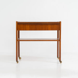 Danish trolley / sidetable in teak, 1960s A simple rolling sidetable with one drawer featuring a nicely sculpted handle, a warm woodgrain and some brass details on the wheels. In good condition with normal using traces.