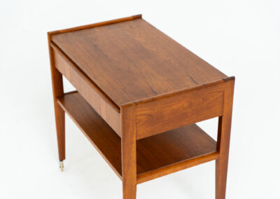 Danish trolley / sidetable in teak, 1960s A simple rolling sidetable with one drawer featuring a nicely sculpted handle, a warm woodgrain and some brass details on the wheels. In good condition with normal using traces.