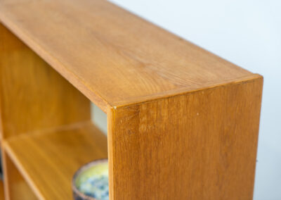 Oak bookcase by Domino Møbler (Denmark, 1960s). A simple bookcase in oak with a white back plate. It’s not very deep so it doesn’t take much space in the room. In good condition with some visible traces of wear and tear.