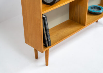 Oak bookcase by Domino Møbler (Denmark, 1960s). A simple bookcase in oak with a white back plate. It’s not very deep so it doesn’t take much space in the room. In good condition with some visible traces of wear and tear.