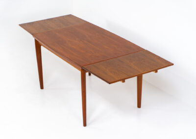 Extendable dining table by Grete Jalk for Glostrup (Denmark, 1960s). A well-know piece by one of Denmarks most prominent designers, Grete Jalk. This teak beauty features signature sculpted legs, nicely rounded solid edges and a unique boat shaped table top with a mesmerizing woodgrain. It is easily extendable with two draw leaves that are cleverly stored underneath the table top. This piece presents itself in amazing condition!
