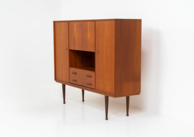 Teak highboard by van Pelt Belgium (Belgium, 1960s). A minimalistic piece made with high quality. It contains two doors with adjustable shelves on this inside, a drop-door with storage space for glasses and bottles, two drawers and an open shelve. The lock of the right door doesn’t work anymore, the key is fixed and the door closes with a magnet. The other locks still work smoothly. The wood is in very good condition with a few spots on the top and on the right side.
