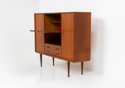Teak highboard by van Pelt Belgium (Belgium, 1960s). A minimalistic piece made with high quality. It contains two doors with adjustable shelves on this inside, a drop-door with storage space for glasses and bottles, two drawers and an open shelve. The lock of the right door doesn’t work anymore, the key is fixed and the door closes with a magnet. The other locks still work smoothly. The wood is in very good condition with a few spots on the top and on the right side.