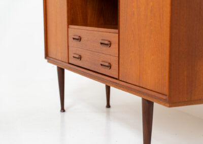 Teak highboard by van Pelt Belgium (Belgium, 1960s). A minimalistic piece made with high quality. It contains two doors with adjustable shelves on this inside, a drop-door with storage space for glasses and bottles, two drawers and an open shelve. The lock of the right door doesn’t work anymore, the key is fixed and the door closes with a magnet. The other locks still work smoothly. The wood is in very good condition with a few spots on the top and on the right side.