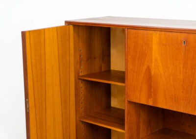 Teak highboard by van Pelt Belgium (Belgium, 1960s). A minimalistic piece made with high quality. It contains two doors with adjustable shelves on this inside, a drop-door with storage space for glasses and bottles, two drawers and an open shelve. The lock of the right door doesn’t work anymore, the key is fixed and the door closes with a magnet. The other locks still work smoothly. The wood is in very good condition with a few spots on the top and on the right side.