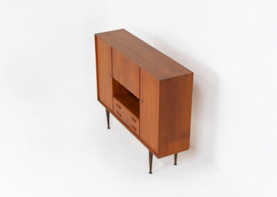 Teak highboard by van Pelt Belgium (Belgium, 1960s). A minimalistic piece made with high quality. It contains two doors with adjustable shelves on this inside, a drop-door with storage space for glasses and bottles, two drawers and an open shelve. The lock of the right door doesn’t work anymore, the key is fixed and the door closes with a magnet. The other locks still work smoothly. The wood is in very good condition with a few spots on the top and on the right side.