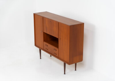Teak highboard by van Pelt Belgium (Belgium, 1960s). A minimalistic piece made with high quality. It contains two doors with adjustable shelves on this inside, a drop-door with storage space for glasses and bottles, two drawers and an open shelve. The lock of the right door doesn’t work anymore, the key is fixed and the door closes with a magnet. The other locks still work smoothly. The wood is in very good condition with a few spots on the top and on the right side.