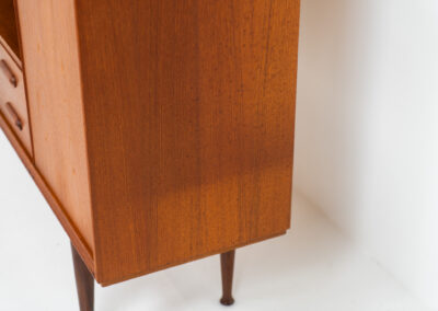 Teak highboard by van Pelt Belgium (Belgium, 1960s). A minimalistic piece made with high quality. It contains two doors with adjustable shelves on this inside, a drop-door with storage space for glasses and bottles, two drawers and an open shelve. The lock of the right door doesn’t work anymore, the key is fixed and the door closes with a magnet. The other locks still work smoothly. The wood is in very good condition with a few spots on the top and on the right side.