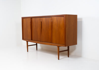 Teak highboard by Gunni Omann for Axel Christensen, ACO Møbler (Denmark, 1960s). A stunning piece containing four sliding doors, lots of storage space and five drawers on the inside. It features the typical sculpted Gunni Omann handles and nice organize shapes. This piece remains in splendid condition!