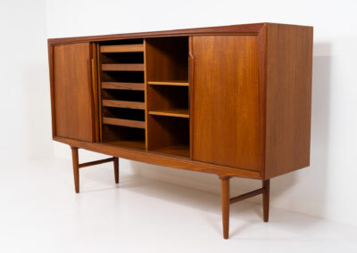 Teak highboard by Gunni Omann for Axel Christensen, ACO Møbler (Denmark, 1960s). A stunning piece containing four sliding doors, lots of storage space and five drawers on the inside. It features the typical sculpted Gunni Omann handles and nice organize shapes. This piece remains in splendid condition!