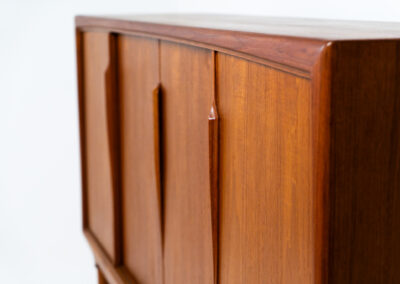 Teak highboard by Gunni Omann for Axel Christensen, ACO Møbler (Denmark, 1960s). A stunning piece containing four sliding doors, lots of storage space and five drawers on the inside. It features the typical sculpted Gunni Omann handles and nice organize shapes. This piece remains in splendid condition!