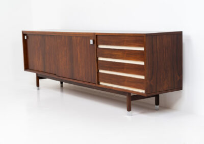 Belgian modernist sideboard in rosewood, 1960s. It features a minimalistic design with sleek lines and chrome details. It offers lots of storage space with two big sliding doors and four drawers. There are clearly traces of use and age like scratches and some color differences, but overall in good condition. We have a matching bar cabinet in stock aswell.