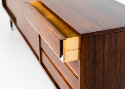 Belgian modernist sideboard in rosewood, 1960s. It features a minimalistic design with sleek lines and chrome details. It offers lots of storage space with two big sliding doors and four drawers. There are clearly traces of use and age like scratches and some color differences, but overall in good condition. We have a matching bar cabinet in stock aswell.