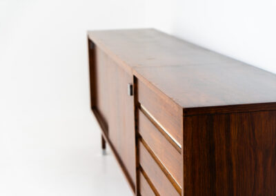Belgian modernist sideboard in rosewood, 1960s. It features a minimalistic design with sleek lines and chrome details. It offers lots of storage space with two big sliding doors and four drawers. There are clearly traces of use and age like scratches and some color differences, but overall in good condition. We have a matching bar cabinet in stock aswell.