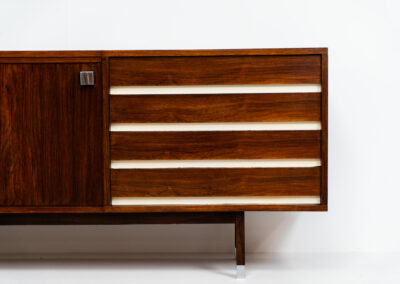 Belgian modernist sideboard in rosewood, 1960s. It features a minimalistic design with sleek lines and chrome details. It offers lots of storage space with two big sliding doors and four drawers. There are clearly traces of use and age like scratches and some color differences, but overall in good condition. We have a matching bar cabinet in stock aswell.