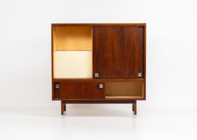 Belgian modernist bar cabinet in rosewood, 1960s. It features a minimalistic design with sleek lines and chrome details. It contains two big and two small sliding doors with lots of storage space on the inside. There are clearly traces of use and age like scratches and some color differences, but overall in good condition. We have a matching sideboard in stock aswell.