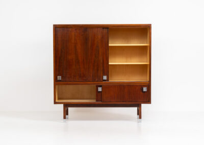 Belgian modernist bar cabinet in rosewood, 1960s. It features a minimalistic design with sleek lines and chrome details. It contains two big and two small sliding doors with lots of storage space on the inside. There are clearly traces of use and age like scratches and some color differences, but overall in good condition. We have a matching sideboard in stock aswell.