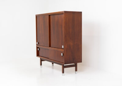 Belgian modernist bar cabinet in rosewood, 1960s. It features a minimalistic design with sleek lines and chrome details. It contains two big and two small sliding doors with lots of storage space on the inside. There are clearly traces of use and age like scratches and some color differences, but overall in good condition. We have a matching sideboard in stock aswell.