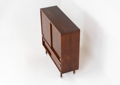 Belgian modernist bar cabinet in rosewood, 1960s. It features a minimalistic design with sleek lines and chrome details. It contains two big and two small sliding doors with lots of storage space on the inside. There are clearly traces of use and age like scratches and some color differences, but overall in good condition. We have a matching sideboard in stock aswell.